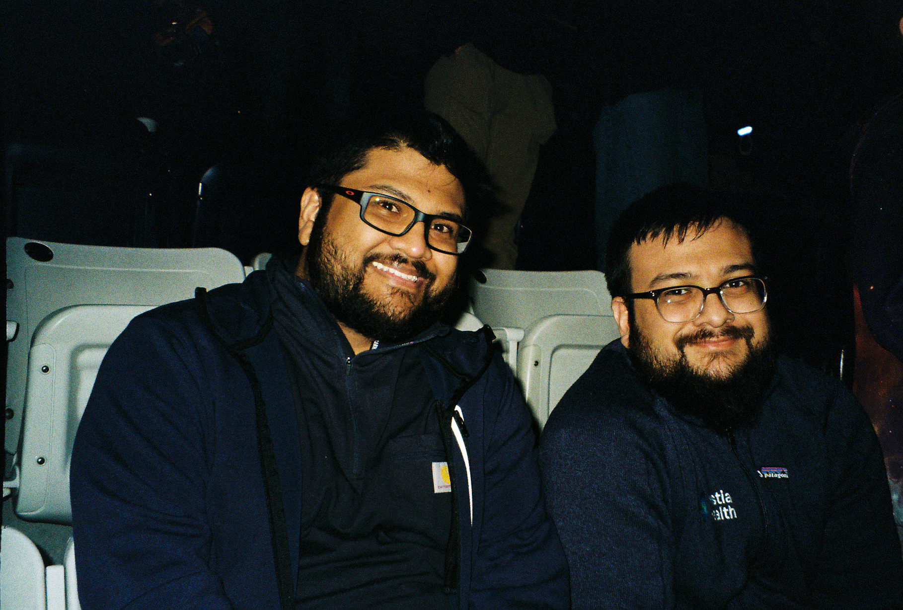 Tabassum's two brothers smiling side by side in the back seat of a car at night