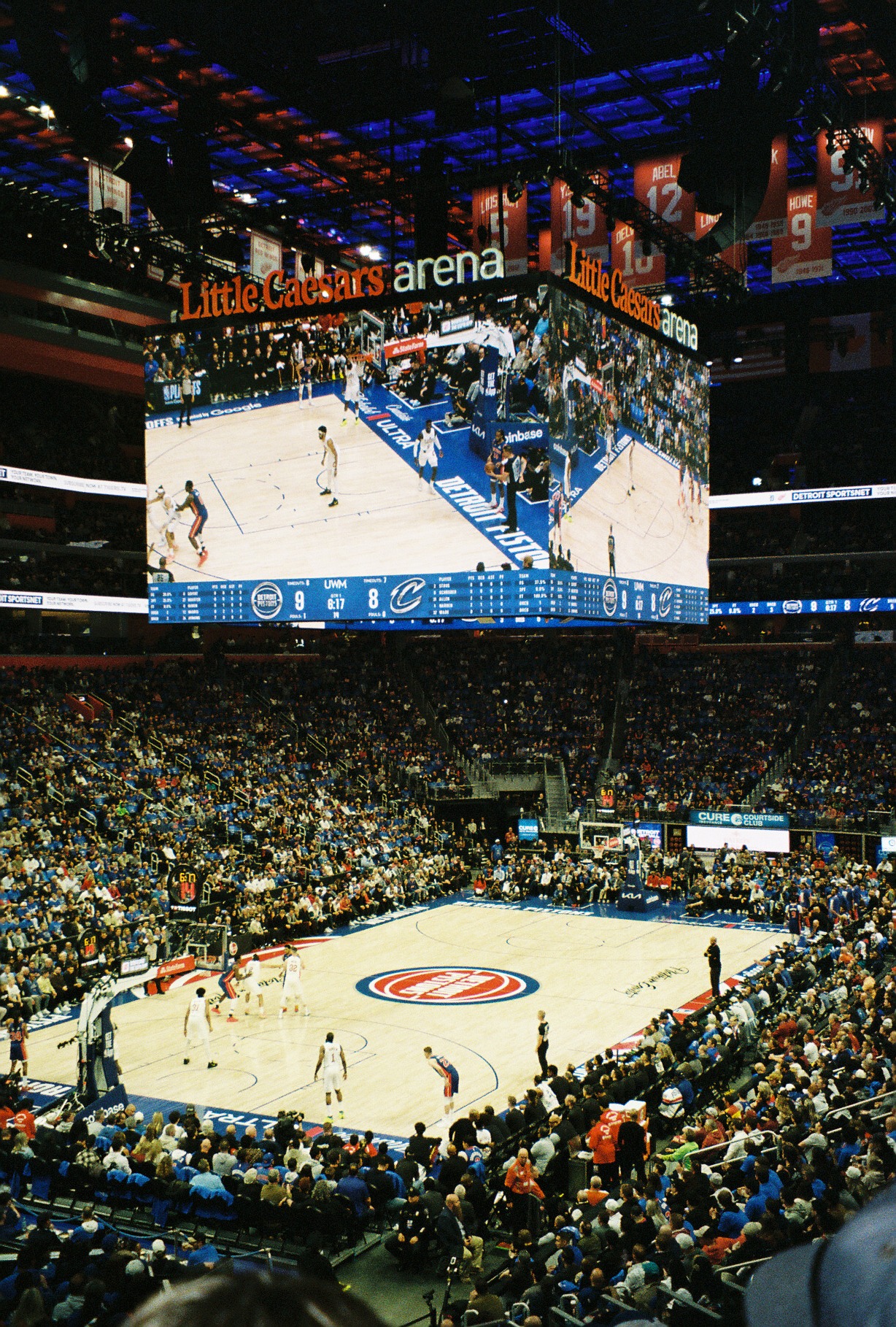 A wide view of Little Caesars Arena during a Pistons playoff game, players on the court below