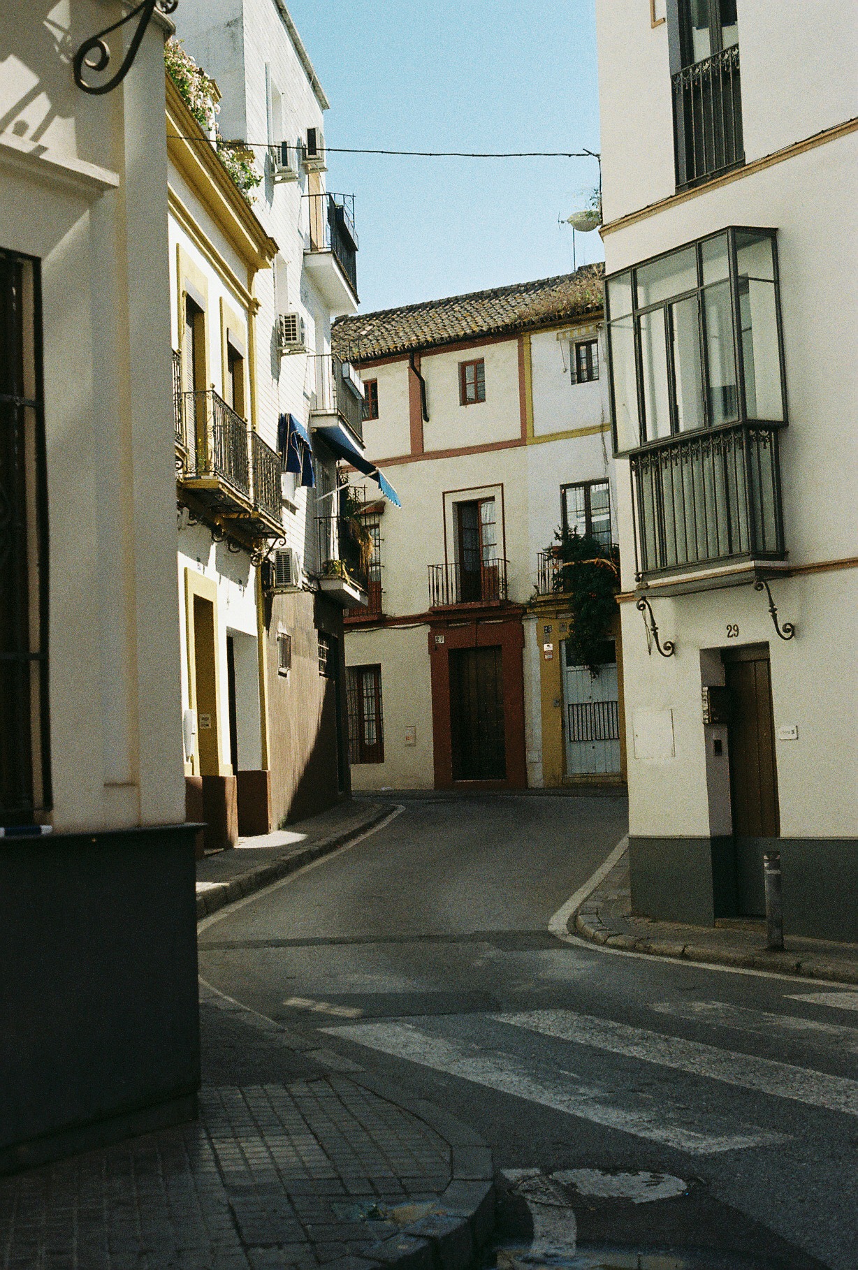 An empty, sunlit street winding between colorful buildings in a Spanish old town