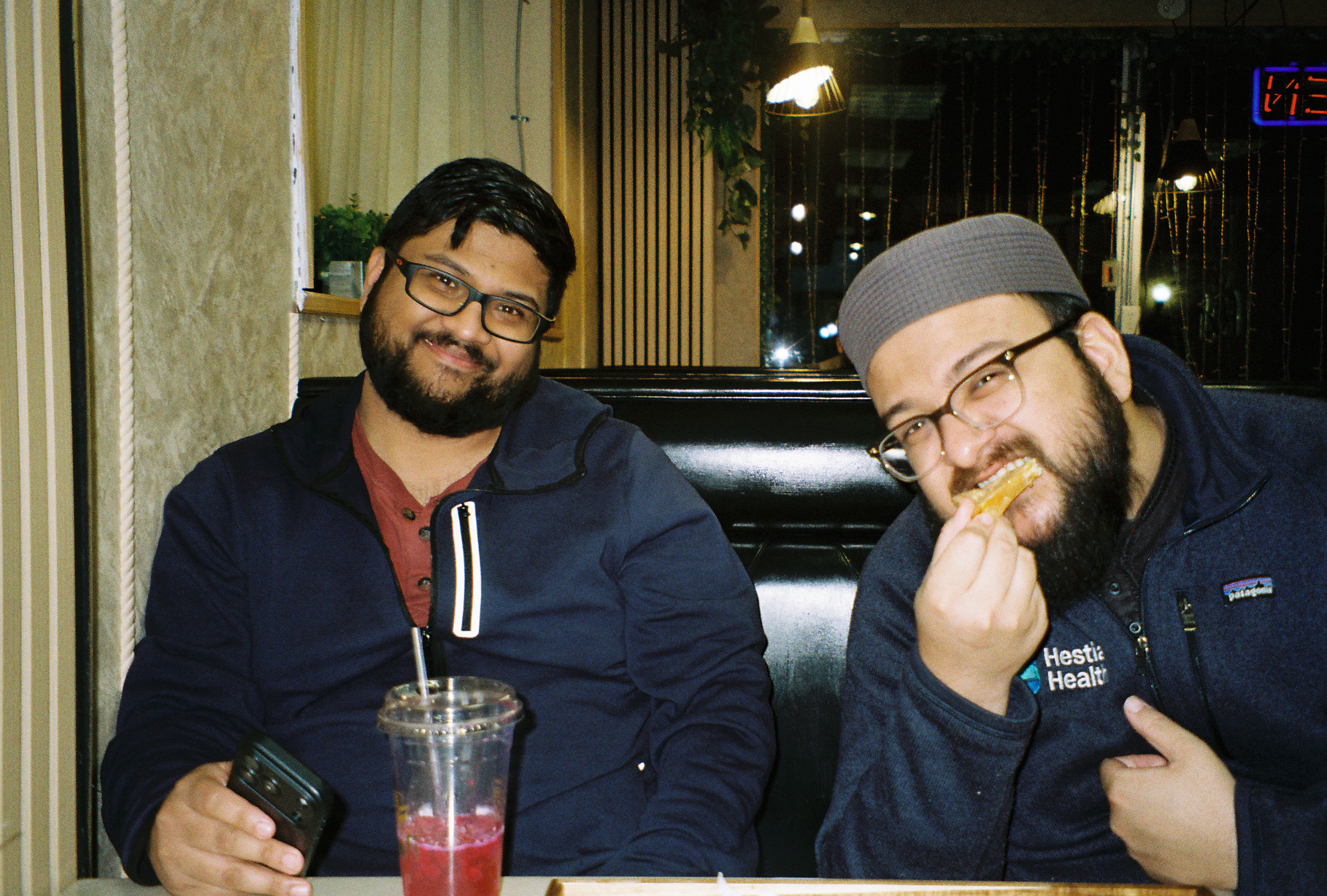 Two men in their mid twenties (Tabassum's brothers) smiling at the camera at a cafe