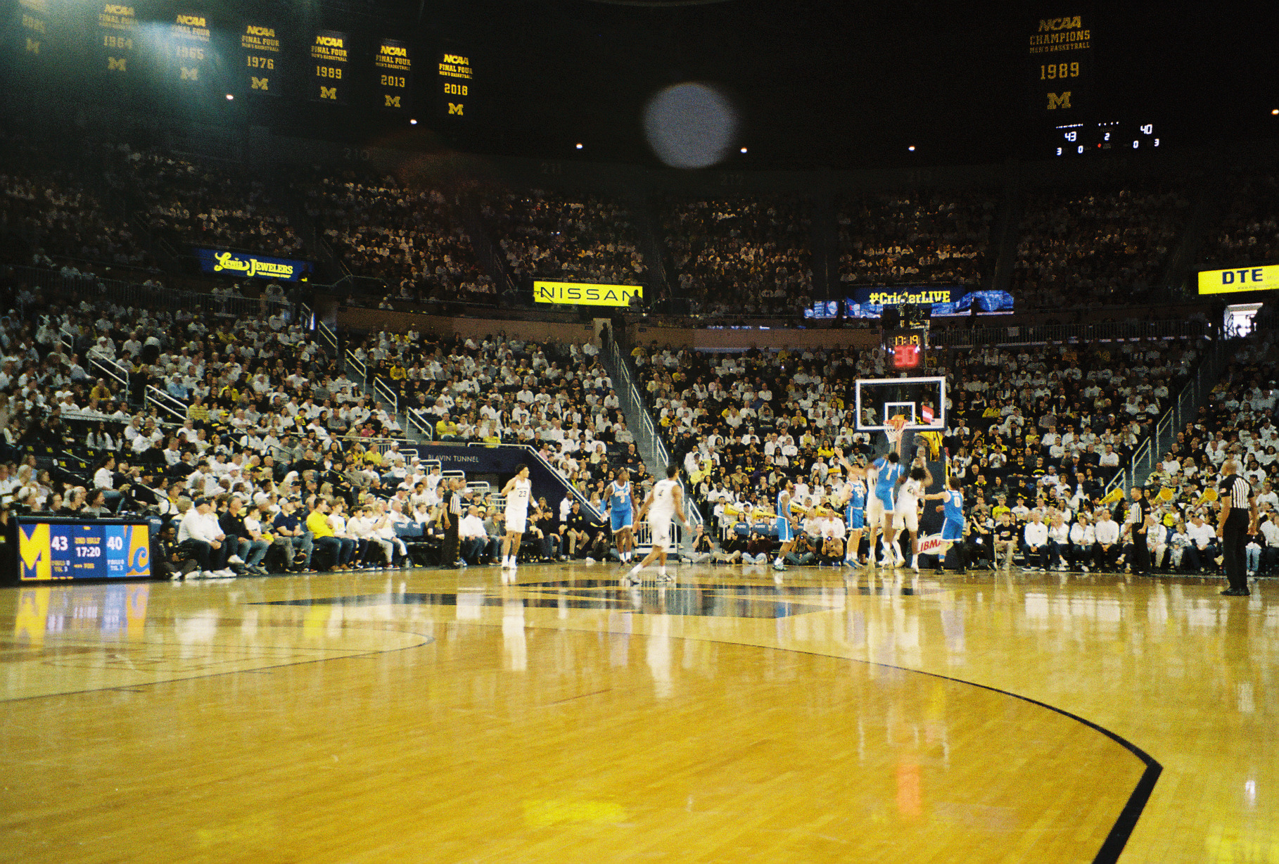Crisler Arena during a Michigan basketball game, championship banners overhead