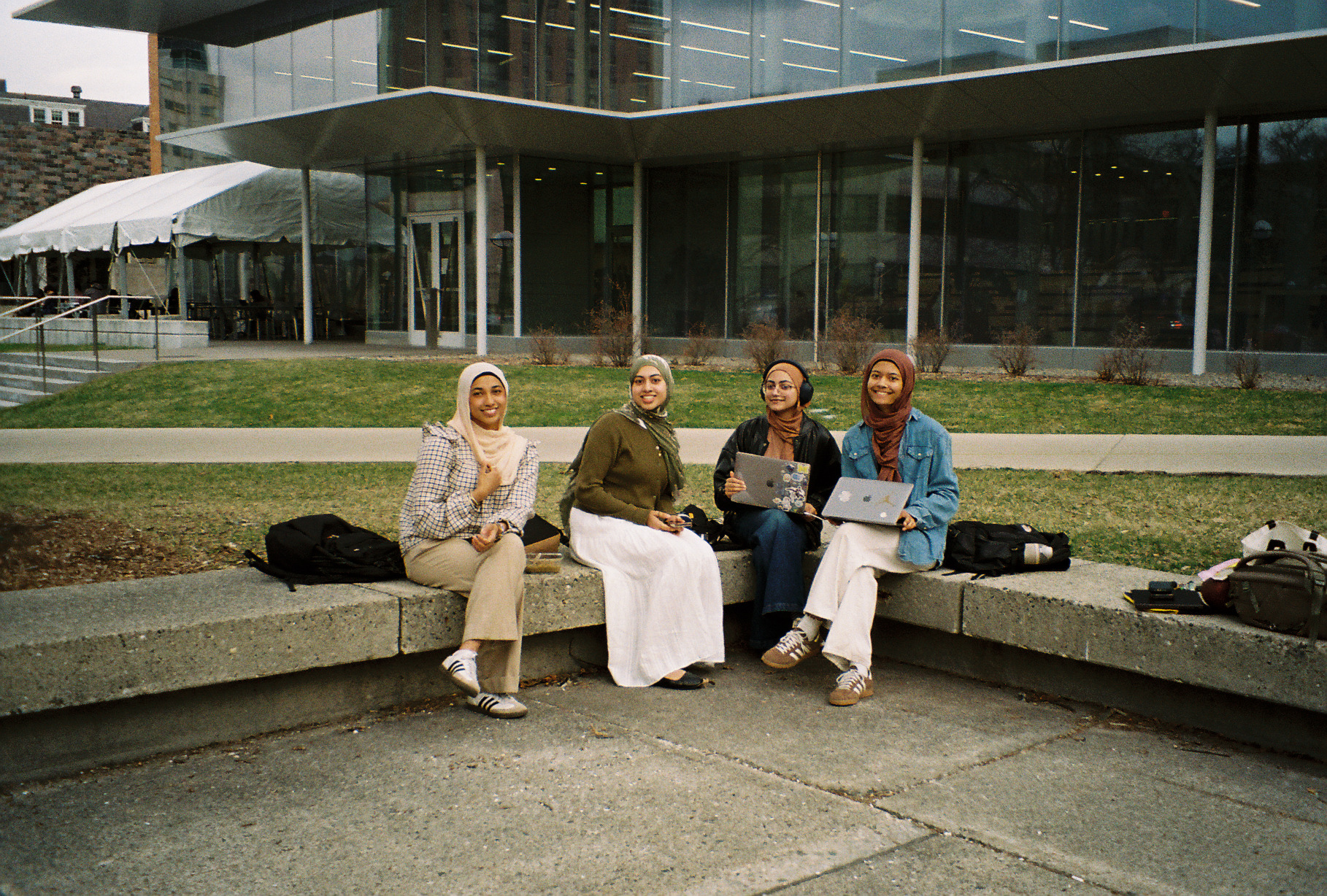 Four friends sitting on curved concrete steps outside the LSA building on campus